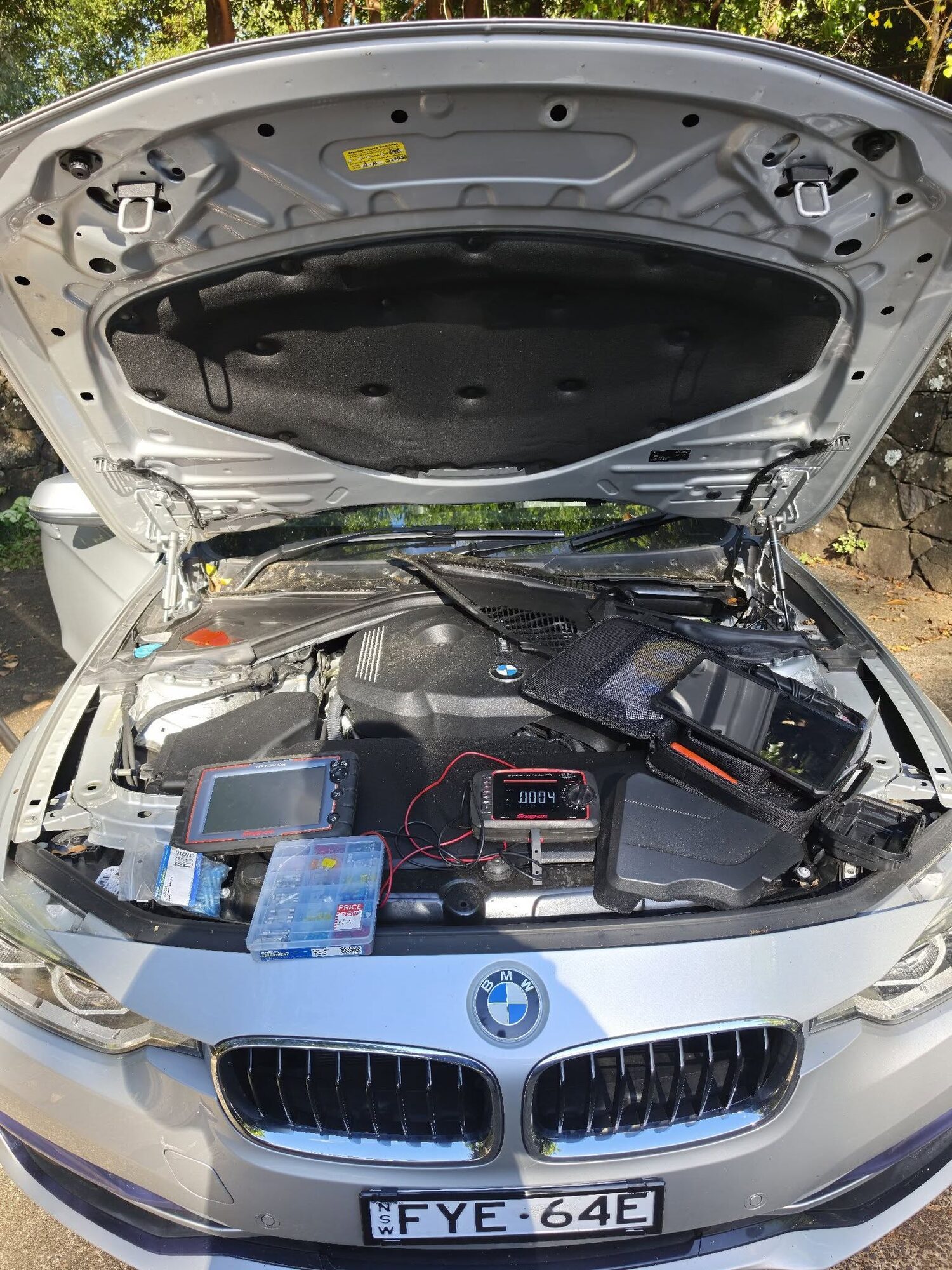 BMW engine bay open with diagnostic equipment connected